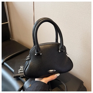 Detail of black lychee grain leather shell bag with silver hardware and top handles