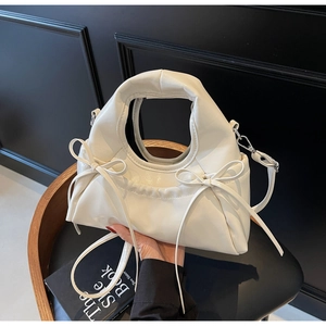 Détail d'un sac en cuir glacé blanc crème avec un nœud délicat et des ferrures argentées