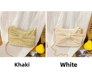 Detail view of khaki and white woven straw bags with oversized bows and gold chain straps