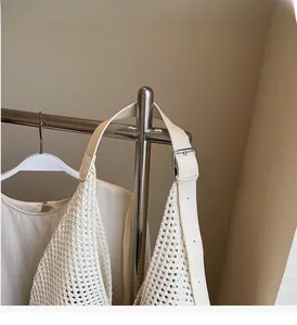 Detail of off-white crochet tote bag featuring adjustable leather strap and silver buckle