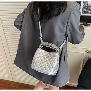 Detail of silver quilted bucket bag featuring rhinestone accents and woven handle