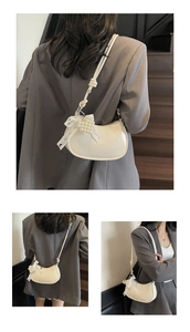 Detail of a creamy white moon bag with lace bow, pearl charms and dual knotted straps