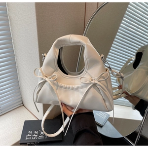 Détail d'un sac à main en cuir PU crème avec nœuds délicats et structure arrondie douce
