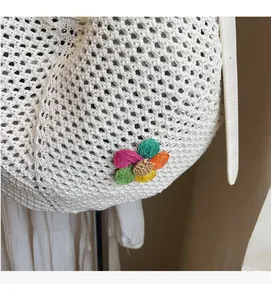 Detail of white crochet tote bag with colorful straw flower and leather strap
