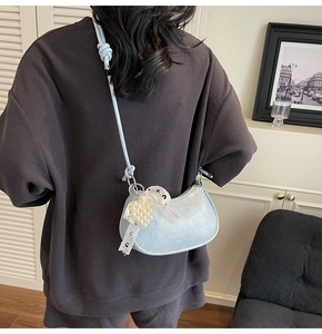 Detail of light blue hobo bag with pearl heart pendant and white lace trim detail
