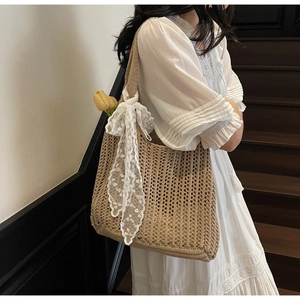 Close-up of khaki woven tote bag featuring white lace bow and a yellow tulip