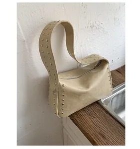 Detail of light beige shoulder bag with silver rivet studs and natural leather texture