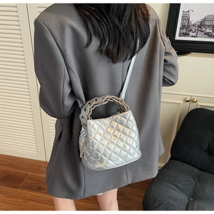 Borsa a secchiello trapuntata argento con manico intrecciato e borchie metalliche su modella