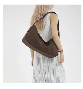 Close-up of brown canvas shoulder bag showing reinforced stitching and metal buckle details