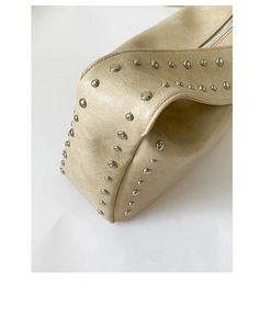 Detailed macro view of the wrinkled texture and silver rivets on a beige leather bag
