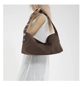 Detail of dark brown canvas hobo bag featuring wide strap with silver metal studs