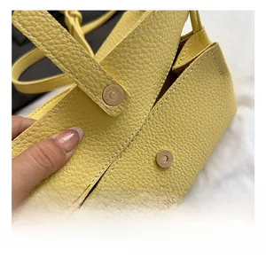 Detail of yellow lychee grain leather bag featuring contrast stitching and magnetic clasp