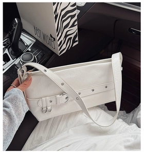 Close-up of white minimalist underarm bag with leather texture and silver buckle detail