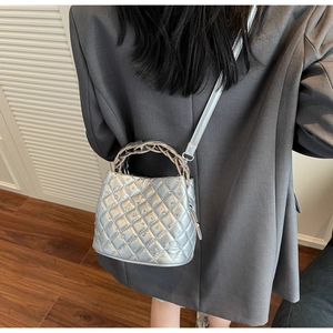 Detail view of silver quilted bucket bag with rhinestones and metal woven handle