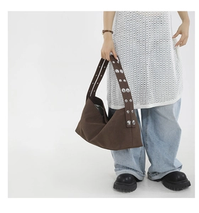 Detail of dark brown canvas hobo bag featuring wide straps and silver metal eyelets