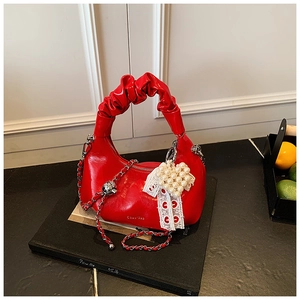Detail of red pleated hobo bag with lace heart charm and silver metal chain strap