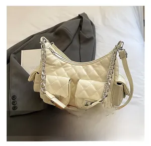 Detailed close-up of cream quilted chain shoulder bag on grey suit and book background
