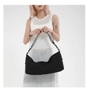 Detail of minimalist black canvas tote bag with metallic grommet studs on the shoulder strap