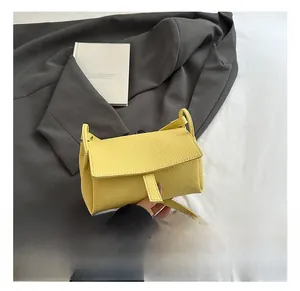 Detail showing bright yellow litchi grain leather texture and strap on a small flap crossbody bag