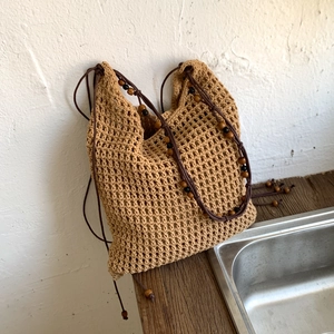 Détail du sac cabas beige tressé avec cordon de serrage marron et perles en bois