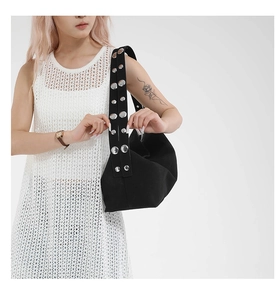 Detail of black canvas dumpling bag with wide shoulder strap featuring silver metal studs