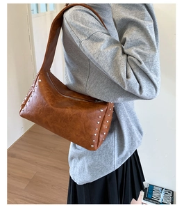 Detail der braunen Vintage-Schultertasche mit silbernen Nieten und Bogen-Design
