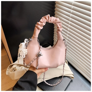 Detail of pink pleated handle and metal chain strap with lace bow and bear charm
