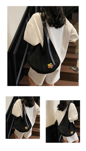 Detail of black crochet tote bag with leather strap and colorful flower charm accessory