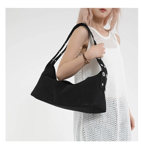 Detail of black canvas shoulder bag featuring stylish silver metal eyelet rivets on the strap