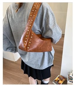 Braune Retro-Schultertasche mit Nieten am Model getragen für einen Punk-Look