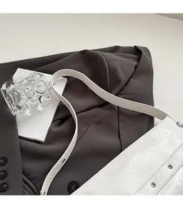 Detail of white crinkled leather shoulder bag with metallic eyelet strap on grey suit