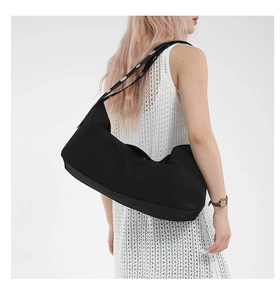 Side view of black crescent crossbody bag with silver eyelets on a fashion model