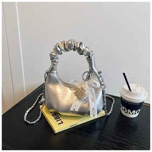 Detail of silver metallic pleated handbag with pearl bow charm and chain strap