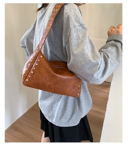 Detail einer braunen Ledertasche mit silbernen Nieten und sicherem Reißverschluss-Design