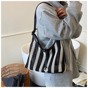 Detail of minimalist black and white striped mesh tote bag with leather strap and metal ring