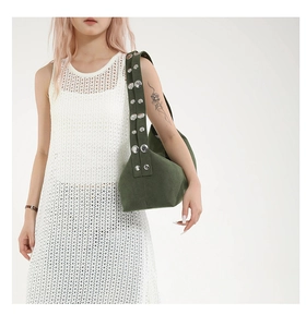 Detail of dark green canvas shoulder bag featuring double-row silver metallic rivets