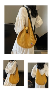 Detail of yellow knit hobo bag with colorful flower accent and black leather strap
