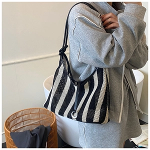 Détail d'un sac cabas tissé à rayures verticales avec une bandoulière en cuir élégante