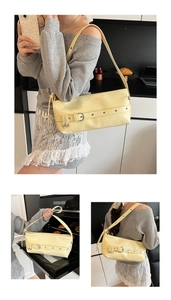 Detail of a creamy yellow underarm bag featuring decorative straps and metal buckles