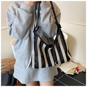 Detail of hollow mesh tote bag with black and white stripes and knotted leather strap