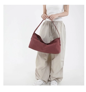 Deep red canvas hobo bag with adjustable silver buckle shown on a model in a studio setting