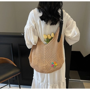 Detail of hand-woven tote bag with colorful crochet flowers and black leather strap