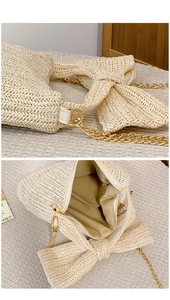 Detail view of straw crossbody bag with large bow, gold chain strap, and zip closure