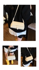Close-up of cream pebble grain leather crossbody bag with detailed stitching and strap
