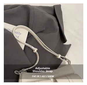 Dettaglio della tracolla regolabile in pelle e fibbia argentata sulla borsa beige