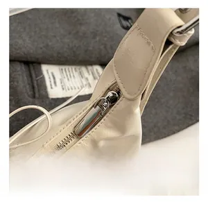 Makroaufnahme der cremefarbenen Ledertasche mit Fokus auf Metallbeschläge und Reißverschluss