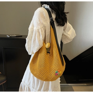 Detail of yellow knit tote bag featuring a colorful woven flower and leather strap