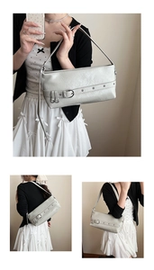 Detail of light grey pleated leather underarm bag with decorative metal belt buckle and studs