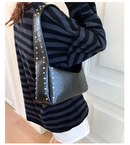 Detail einer schwarzen Unterarmtasche aus Leder mit Vintage-Silbernieten an der Seite