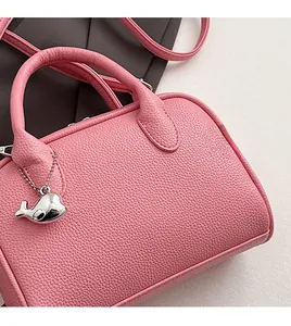 Detailed macro view of pink litchi grain leather texture and whale pendant on boston bag